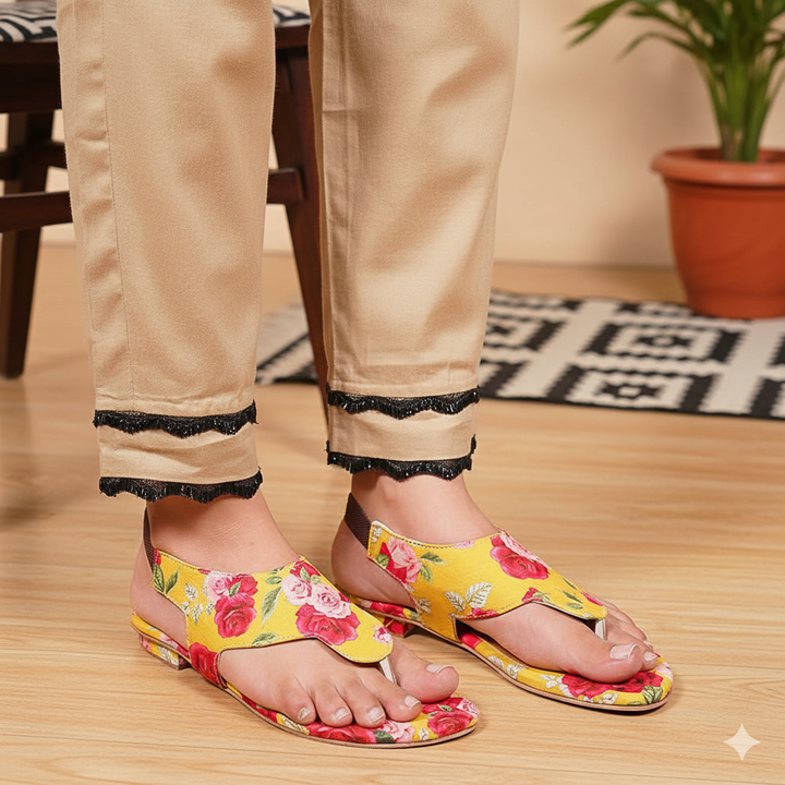 Person wearing floral sandals on a wooden floor with a plant in the background