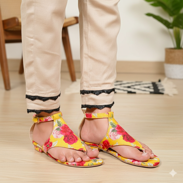 Person wearing yellow floral sandals on a light wooden floor.