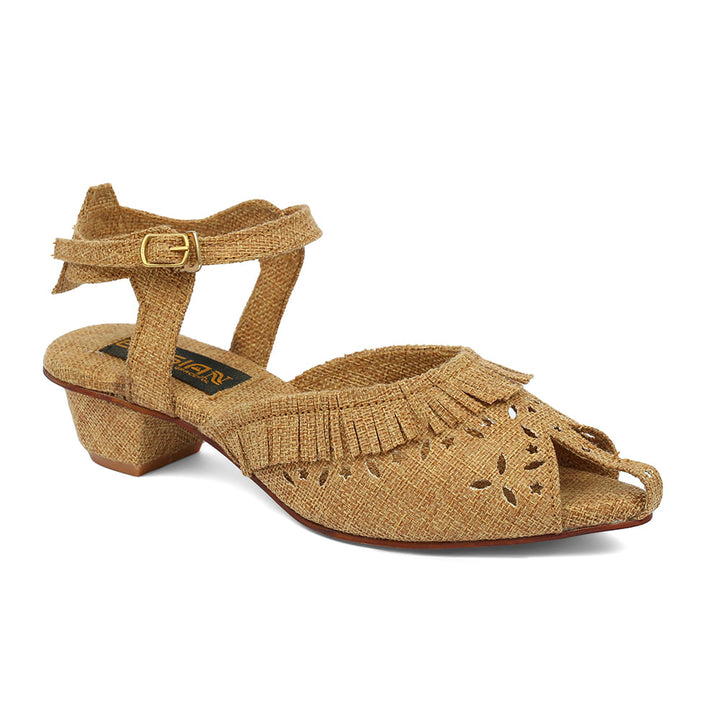 A tan-colored sandal with a jute upper and fringe detail, featuring a buckle ankle strap and a low heel.