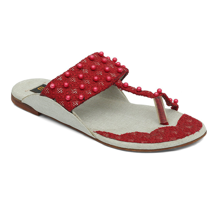 A red flat sandal with pearl embellishments and a flat sole.