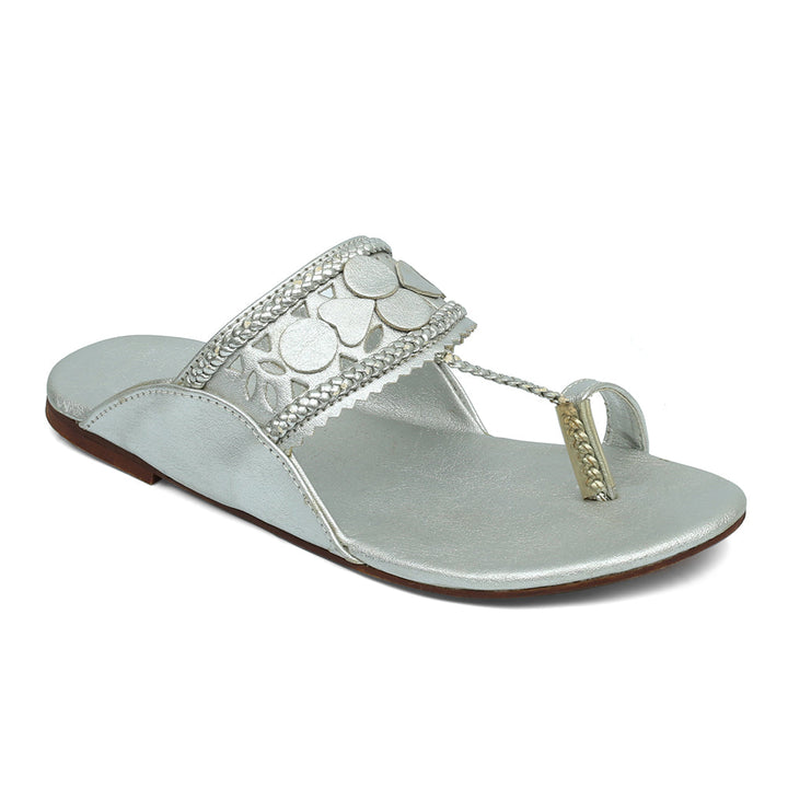 A silver flat sandal with embellishments on the strap and a closed toe.
