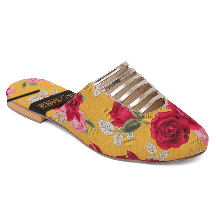 A pair of yellow printed mules with floral designs, including roses and leaves, and metallic accents on the straps.