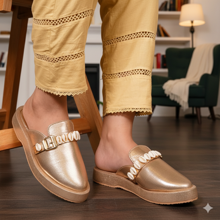 Gold slip-on shoes with decorative elements worn indoors.