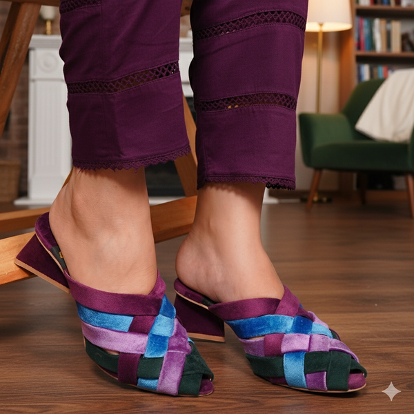 Purple woven sandals worn with purple pants on a wooden floor.