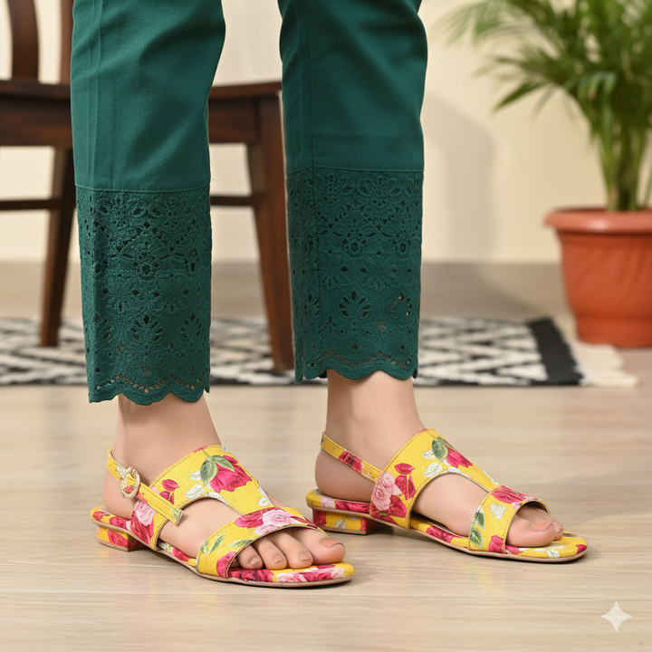 Person wearing floral sandals and green pants on a wooden floor.
